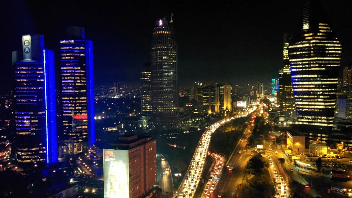 Gece Levent: mavi ışıklı Sabancı Center kuleleri, çevredeki ofis kuleleri ve Büyükdere Caddesi'ndeki trafik (temsilî görsel)