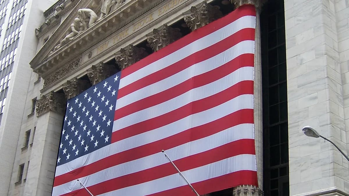 Een reusachtige Amerikaanse vlag over de gevel van de New York Stock Exchange, met een deel van het fronton erboven (illustratieve afbeelding)