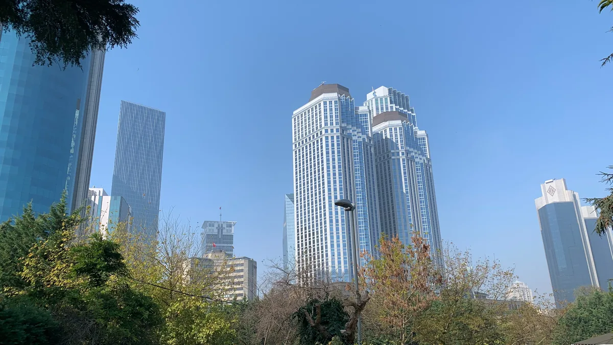 Levent'teki İş Kuleleri (Türkiye İş Bankası genel müdürlüğü), önde parkın ağaçları (temsilî görsel)